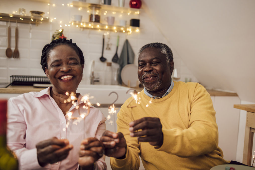 Portrait of African American senior couple lighting sparklers celebrating New Year's eve at home